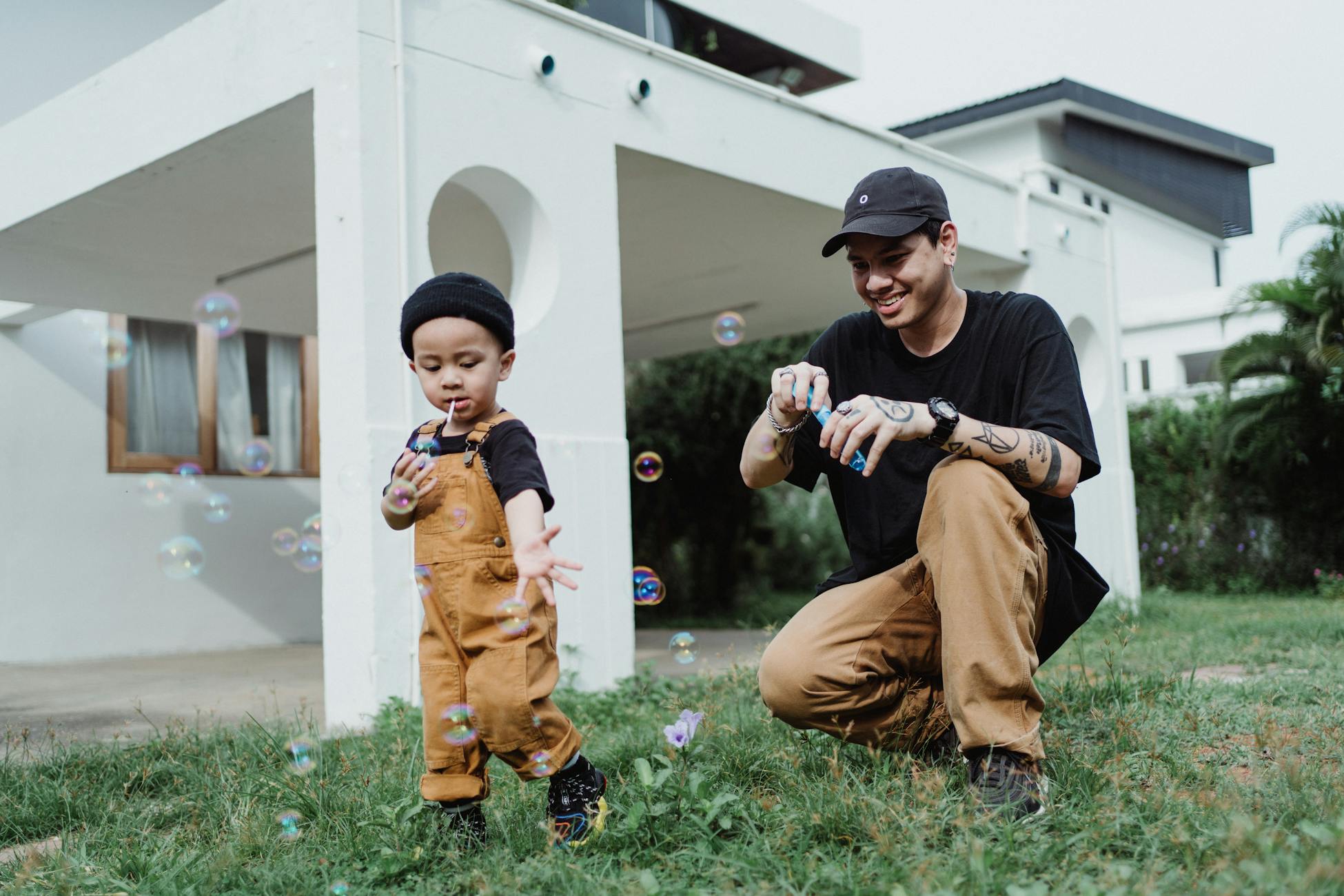 A father and son share joyful moments blowing bubbles in their backyard garden.
