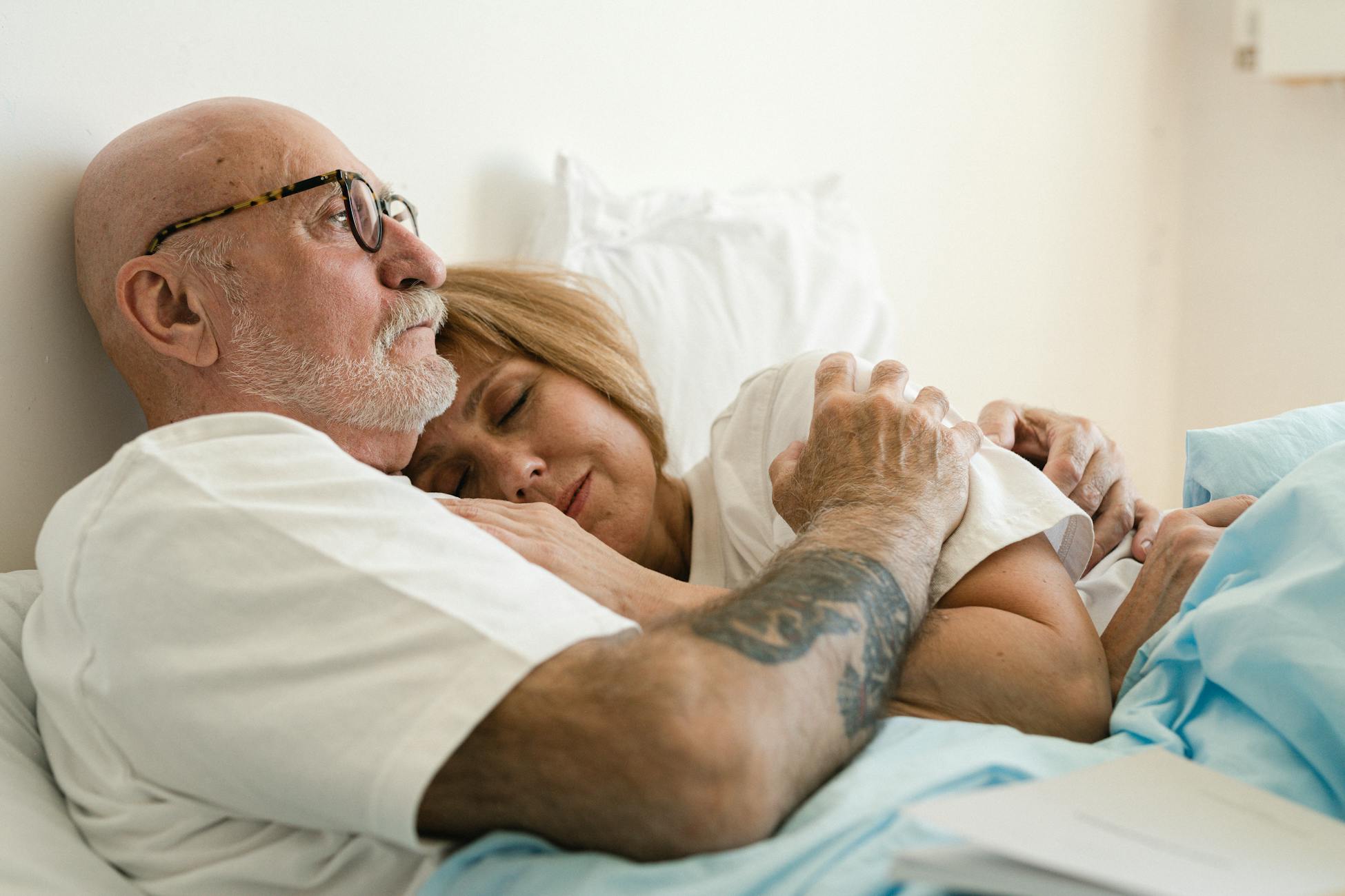 Senior couple lovingly embracing in bed, showcasing warmth and affection in their bedroom.