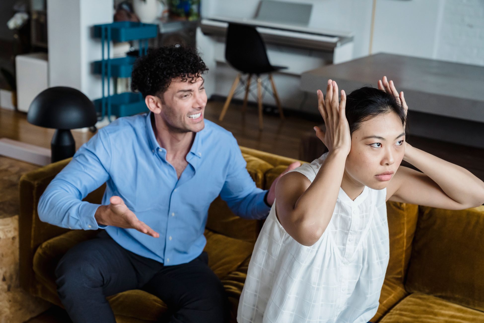 A man and woman in a heated argument sitting on a couch indoors.
