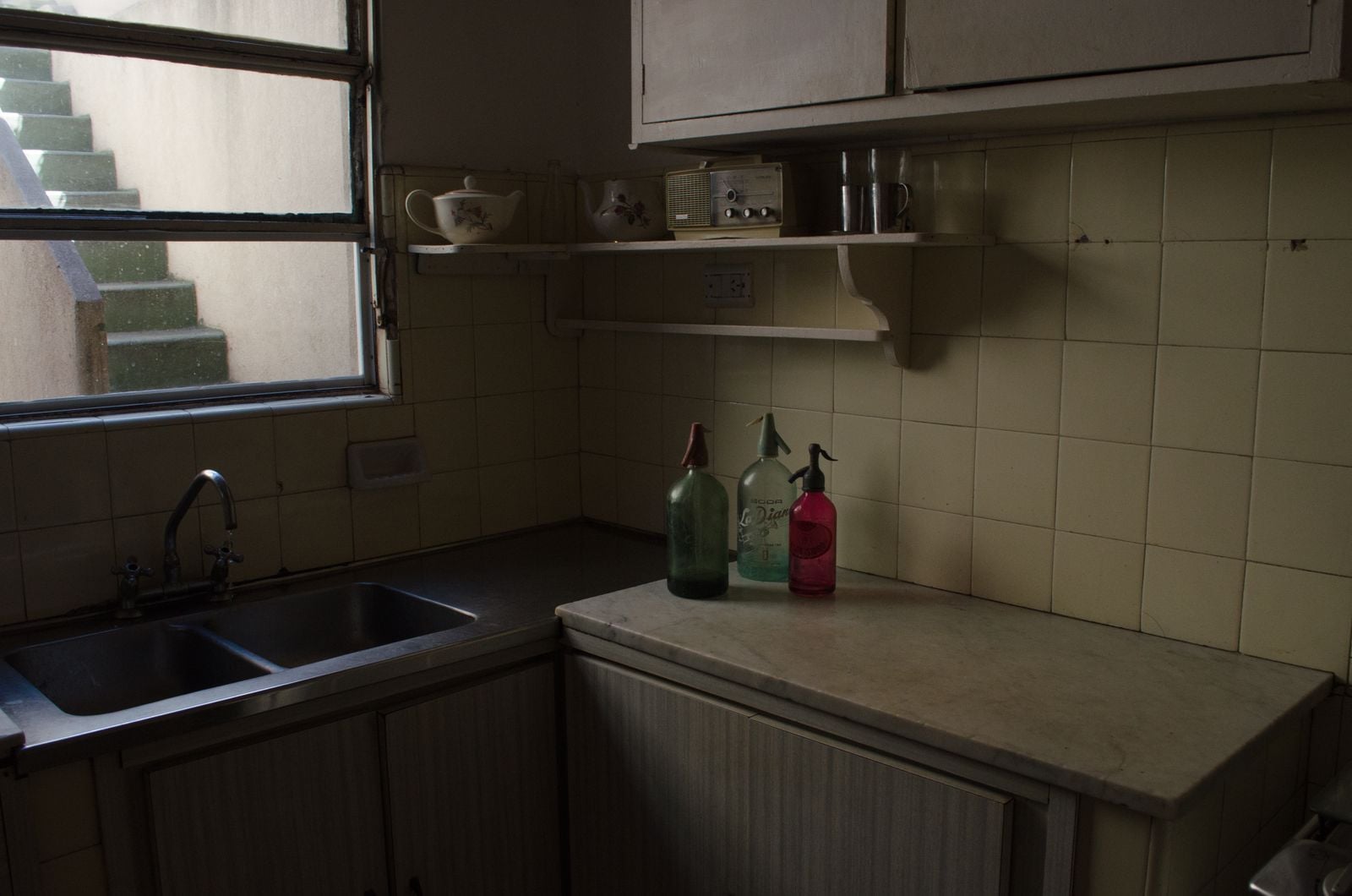 The habit of keeping the radio on in an empty house often has less to do with company than with the memory of a kitchen where a voice in the background meant someone was home and nothing bad was happening yet