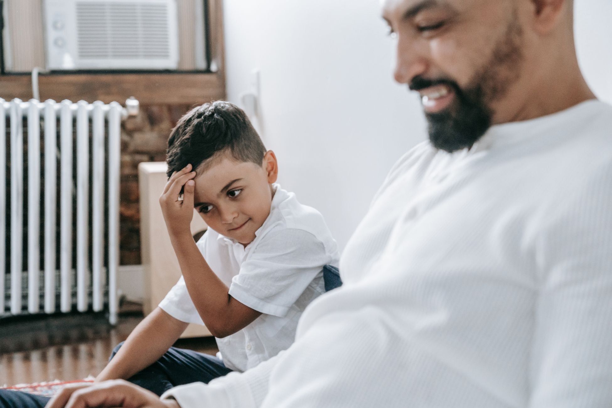A heartwarming moment captures a father and son bonding at home, showcasing togetherness.