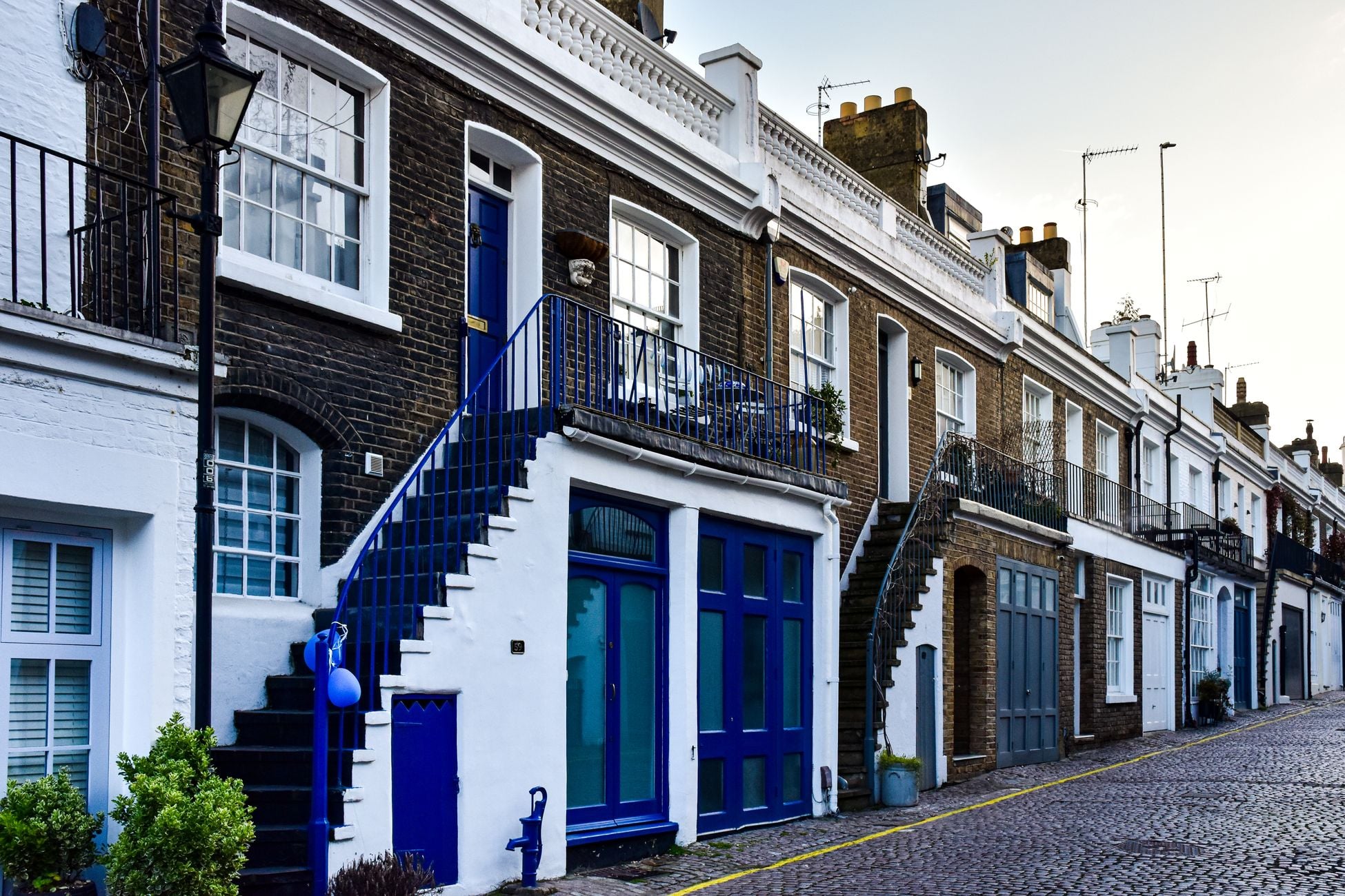 Elegant row of classic London townhouses with vibrant facades and cobblestone street.