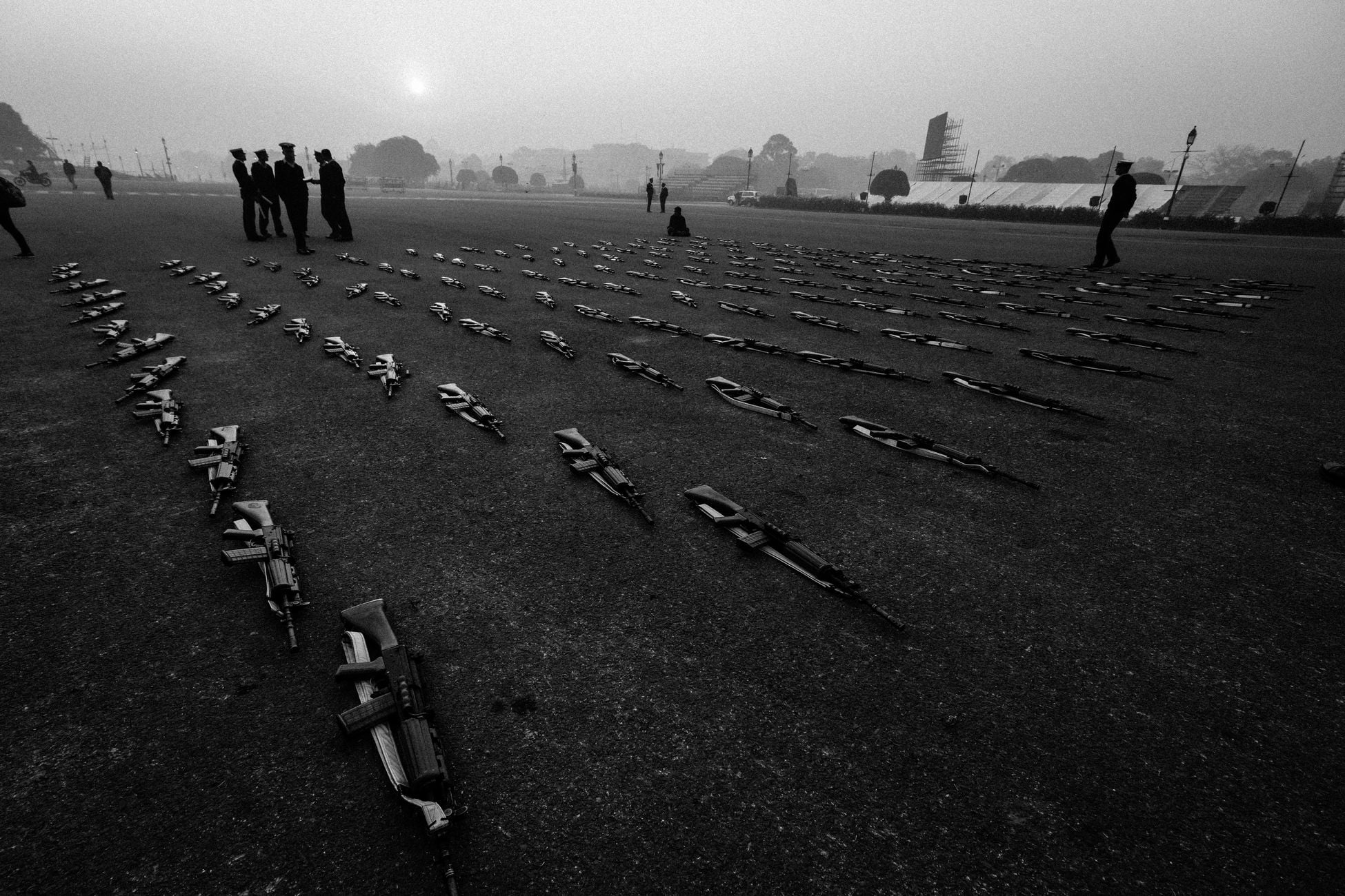 Grayscale photo of soldiers and rifles arranged in a field in New Delhi.