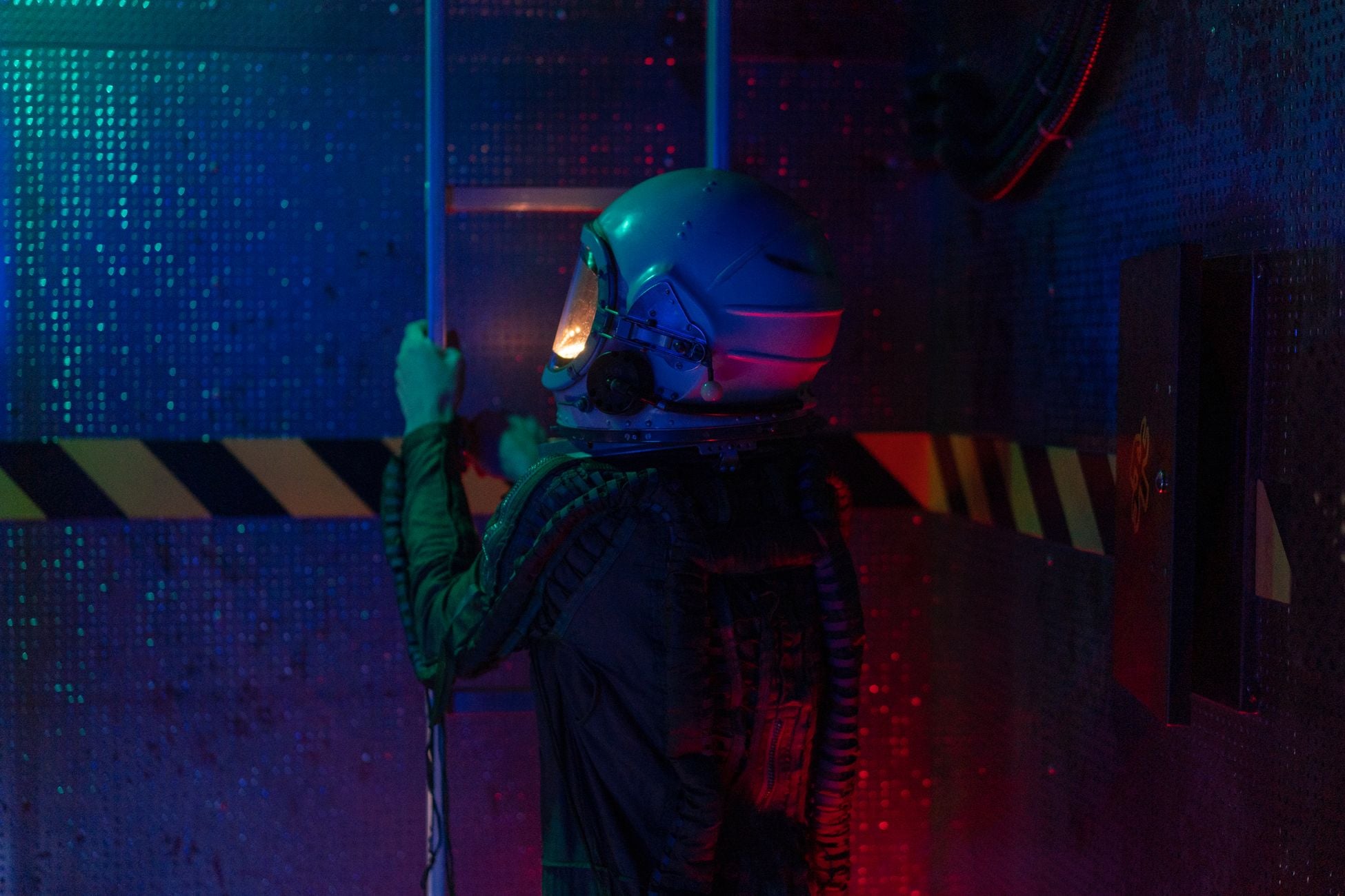 A person in a spacesuit climbs a ladder in a sci-fi environment with colorful lights.