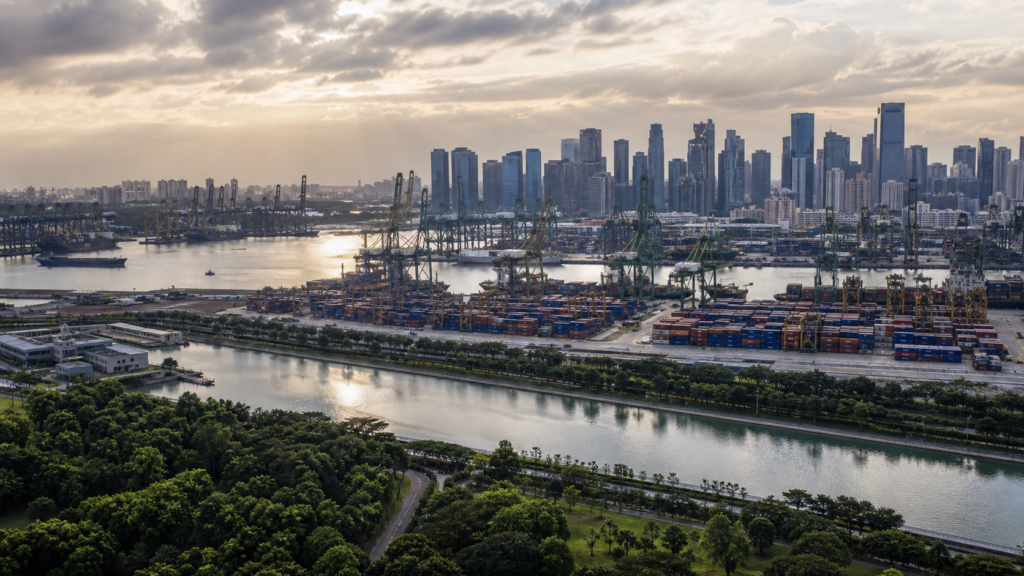 Singapore skyline beyond a container port, engineered waterway and tropical greenery